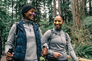 Two mountain climbers apply sunscreen on their nose